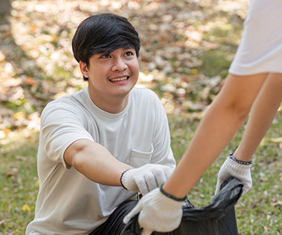 young man smiling while receiving a trash bag during a community cleanup event promoting teamwork and environmental awareness 6 actions for a cleaner world